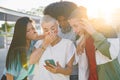 Cheerful group of friends looking smart phone surprised and excited outdoors. Smiling young people. Royalty Free Stock Photo