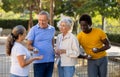 Cheerful group of multiracial mature adult people standing together and talking during a break in petanque game outside Royalty Free Stock Photo