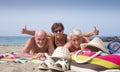 Cheerful group of three people friends mature and senior enjoying together holidays at the beach gesturing ok sign - active Royalty Free Stock Photo