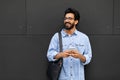 Cheerful guy in casual standing over grey wall, holding cellphone Royalty Free Stock Photo