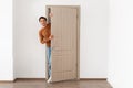 Cheerful guy looking out of door standing in doorway