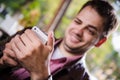 Cheerful guy at the restaurant outdoors using a mobile phone, hands close up Royalty Free Stock Photo