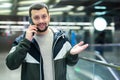 Cheerful guy talking on phone near escalator at subway station Royalty Free Stock Photo