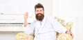 Cheerful guy in white bathrobe enjoying morning coffee. Bearded man sitting in beautiful antique armchair. Energetic Royalty Free Stock Photo