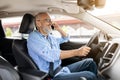 Cheerful elderly man driver talking on phone while driving car Royalty Free Stock Photo