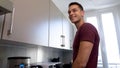 Cheerful handsome guy cooking dinner, waiting for friends, modern kitchen