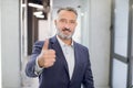 Cheerful handsome middle aged bearded Caucasian businessman, wearing shirt and jacket, showing thumbs up, posing and Royalty Free Stock Photo