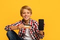 Cheerful handsome teen blond boy pupil show smartphone with blank screen and credit card