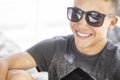 Cheerful handsome teenage boy smiling in modern sunglasses with digital tablet. Happy male teenager having fun spending leisure Royalty Free Stock Photo