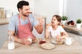 Cheerful handsome young male and little child eat pancakes together, drinks fresh milk, enjoy breakfast at kitchen Royalty Free Stock Photo