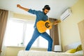 Cheerful handsome young man playing guitar and smiling in new cozy apartment Royalty Free Stock Photo