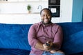 Cheerful and happy African-American man with dreadlocks holding TV remote controller Royalty Free Stock Photo