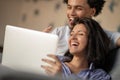 Cheerful happy African American young marriage laughing while watching movie on laptop computer at home interior. Royalty Free Stock Photo