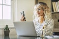 Cheerful happy businesswoman doing phone call in front of a laptop computer in home office workplace desk. Smiling freelance Royalty Free Stock Photo