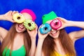 Cheerful happy comic sisters holding donutes against eyes Royalty Free Stock Photo