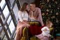 Cheerful happy family with little baby girl in aesthetic cozy home interior near festive Christmas tree. Beautiful