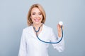 Cheerful happy female doctor listening palpitation with a stethoscope over grey background