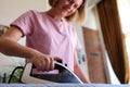 Cheerful happy housewife irons clothes on ironing board Royalty Free Stock Photo