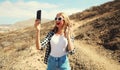 Cheerful happy laughing young woman taking selfie with mobile phone or talking on video call waving hand greeting on a hiking Royalty Free Stock Photo