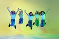 Cheerful, happy, little girls, children in casual sporty style clothes jumping, dancing against green studio background Royalty Free Stock Photo