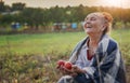 Cheerful happy mature senior woman holding red apples sitting in her garden Royalty Free Stock Photo