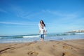 Cheerful happy mom catches her daughter while running barefoot, playing together on beach, leaving footsteps on wet sand Royalty Free Stock Photo