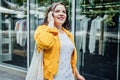 Cheerful happy plus size curvy woman talking on phone outdoors. Outdoor portrait of happy smiling candid plus size woman Royalty Free Stock Photo