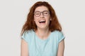Cheerful happy red-haired young woman in glasses laughing out loud