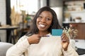 Cheerful happy smiling African-American woman holding empty credit card and points finger on it Royalty Free Stock Photo