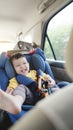 Happy smiling Asian little boy in safety car seat Royalty Free Stock Photo