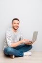 Cheerful happy smiling man sitting on floor with laptop Royalty Free Stock Photo