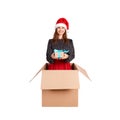 Cheerful happy woman in dress and christmas hat having fun while sitting in the big gift box and giving present witj blue ribbon. Royalty Free Stock Photo