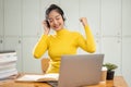 A cheerful Asian female college student enjoys listening to music on her headphones in a library Royalty Free Stock Photo