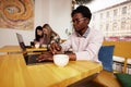 Cheerful and happy young black teenager messaging online on laptop, checking social media news feed, using free wireless