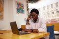 Cheerful and happy young black teenager messaging online on laptop, checking social media news feed, using free wireless