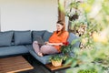 Cheerful happy young redhead woman relaxing with laptop in the yard of the house in summer. Casual beautiful woman is Royalty Free Stock Photo