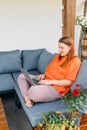 Cheerful happy young redhead woman relaxing with laptop in the yard of the house in summer. Casual beautiful woman is Royalty Free Stock Photo