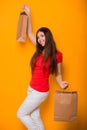 Cheerful, happy, young woman with paper bags in hands standing on a yellow background. Shopping, discount day, black friday. Royalty Free Stock Photo