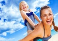 Cheerful healthy mother and child on seashore having fun time