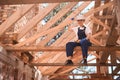 Cheerful high-qualified woman roofer sitting on wooden girder