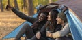 Cheerful hikers taking selfie on smartphone, sitting in tent