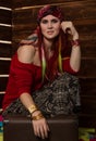 Cheerful hippie boho redhead woman poses with old suitcase on a wooden wall background