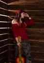 Cheerful hippie boho redhead woman standing with guitar on a wooden wall background