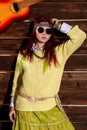 Cheerful hippie boho redhead woman in sunglasses poses on a wooden wall background