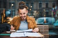 Cheerful hipster with sketchbook in urban cafe Royalty Free Stock Photo