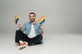 Cheerful homosexual man holding lgbt flags