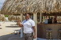 Cheerful hotel staff member near the beachside restaurant, warmly smiling and giving a thumbs-up