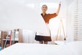 Cheerful housekeeper makes a bed in a large room.