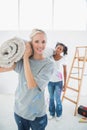 Cheerful housemates carrying rolled up rug in new home