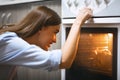 Cheerful housewife cooking dinner in oven at home